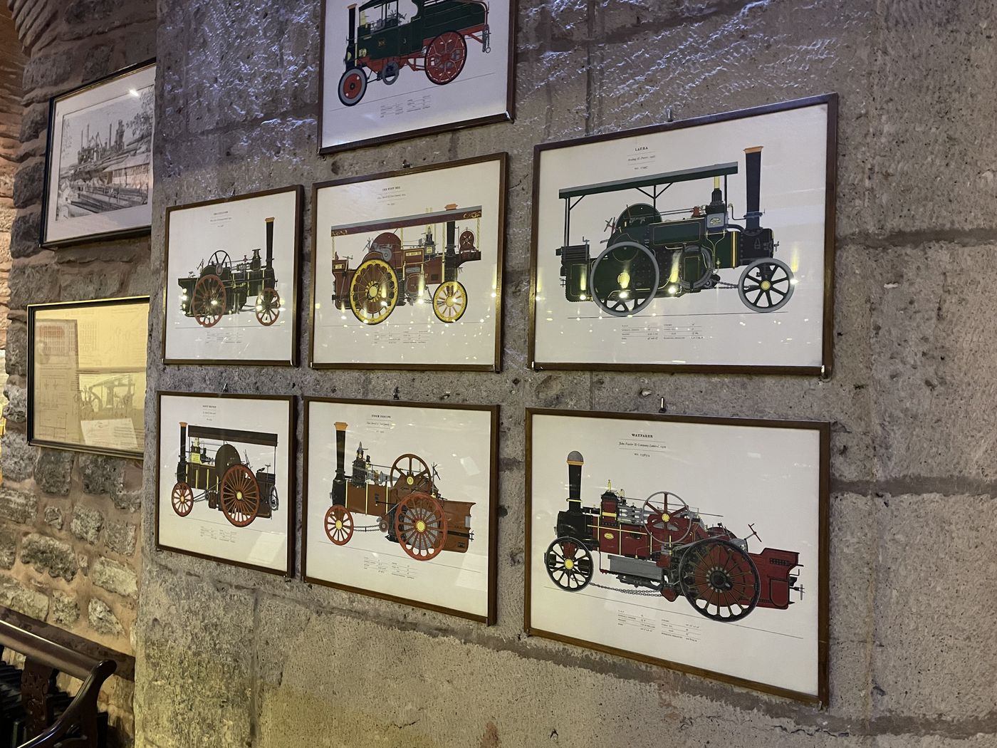 Framed prints of steam traction engines on a stone wall at the Rahmi M. Koç Museum